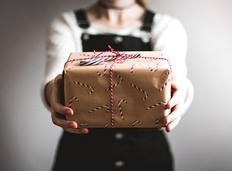 Person hält verpacktes Weihnachtsgeschenk in den Händen